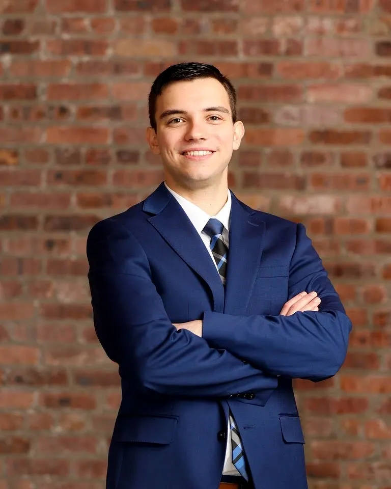 A man in a suit and tie standing with his arms crossed.